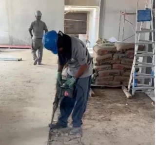 Homem usando martelete para quebrar piso